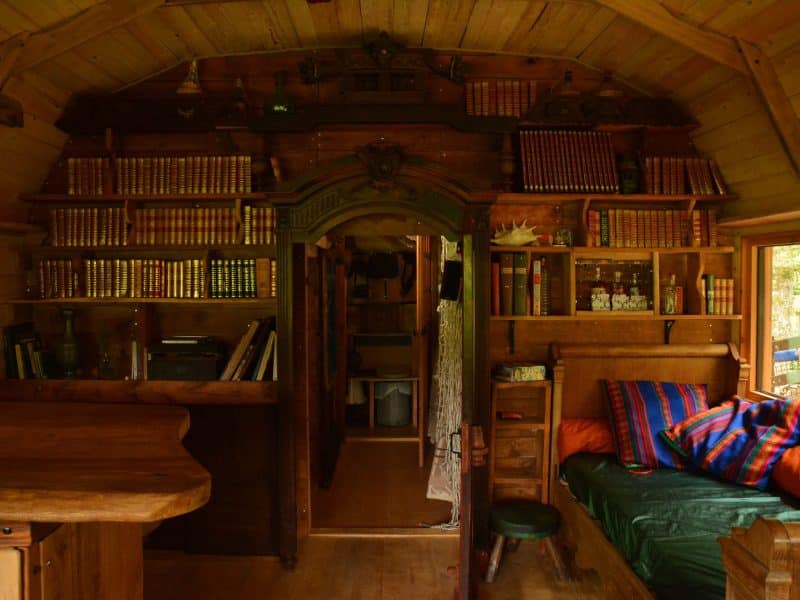 Intérieur dune cabane en bois, avec des étagères remplies de livres et un coin salon accueillant.