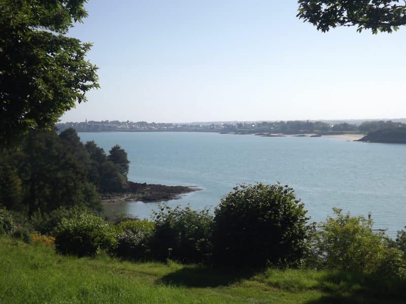 Vue panoramique sur la mer depuis un gîte, entouré de verdure luxuriante.