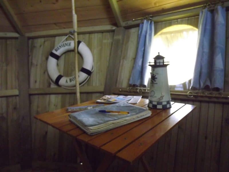 Cabane de pêcheur avec une table en bois et une lampe en forme de phare.
