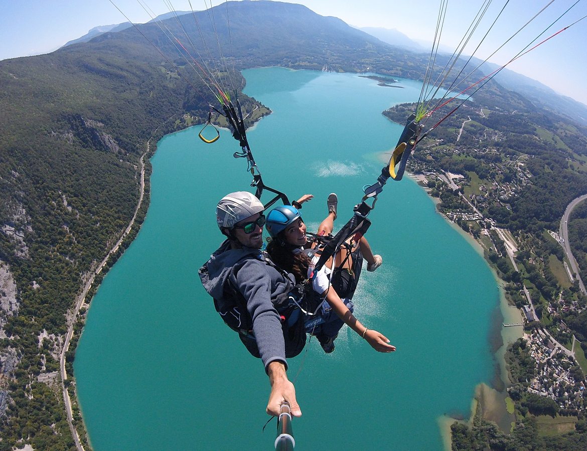 Parapente au-dessus d'un lac turquoise, offrant une vue imprenable sur la nature environnante.