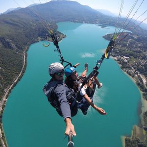 Parapente au-dessus d'un lac turquoise, offrant une vue imprenable sur la nature environnante.