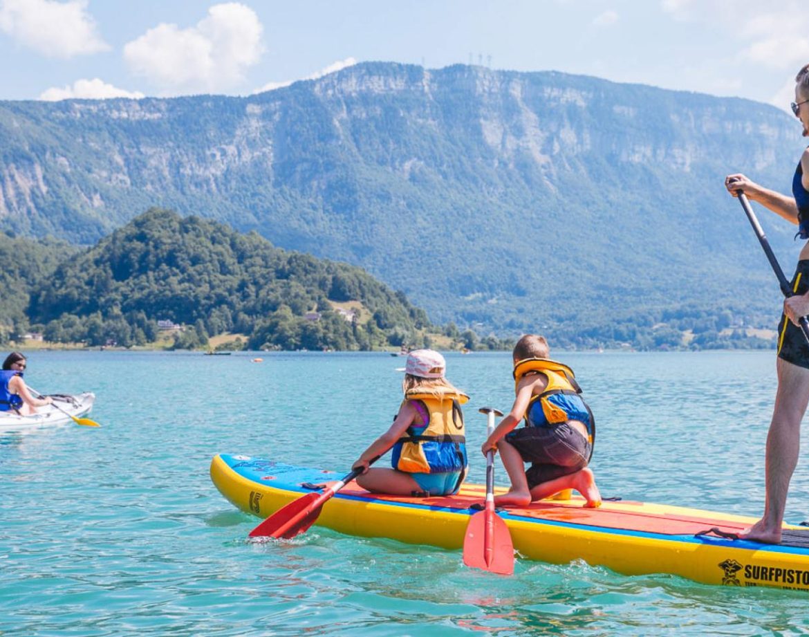 Paddle sur un lac turquoise, en famille, avec des montagnes en arrière-plan. Hébergement insolite à