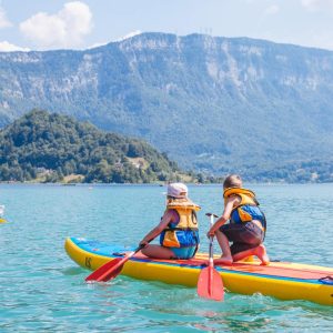 Paddle sur un lac turquoise, en famille, avec des montagnes en arrière-plan. Hébergement insolite à