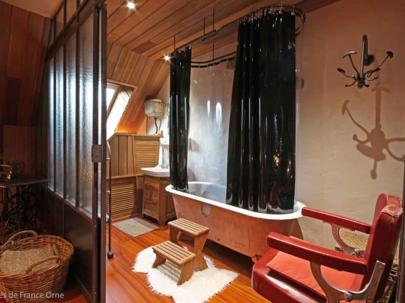 Chambre dhôtes avec baignoire vintage et décoration en bois chaleureux.