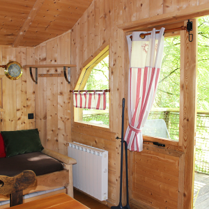 Intérieur chaleureux d'un chalet en bois, avec des rideaux rayés et une vue sur la nature.