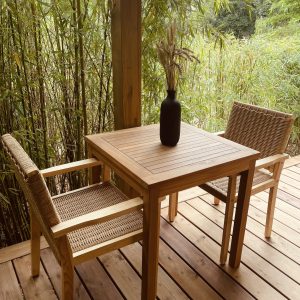 Un hébergement insolite avec une terrasse en bois, deux chaises et un vase décoratif.