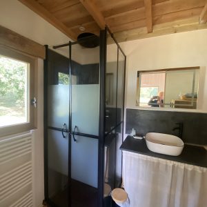 Salle de bain moderne dans un hébergement insolite, avec douche vitrée et lavabo design.