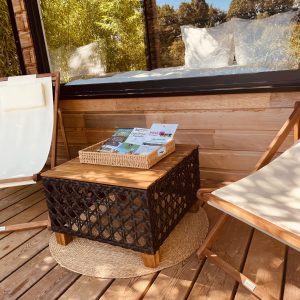 Espace détente en bois avec chaises longues et table, idéal pour un hébergement insolite.