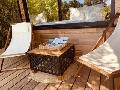 Espace détente en bois avec chaises longues et table, idéal pour un hébergement insolite.