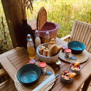 Table en bois avec petit-déjeuner campagnard, vue sur la nature, ambiance chaleureuse.