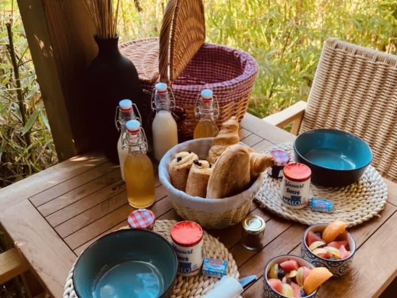 Table en bois avec petit-déjeuner, vue sur la nature, hébergement en pleine campagne.