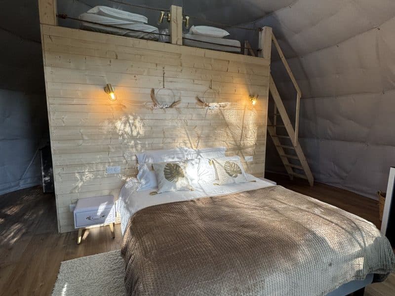 Dôme écologique avec lit douillet, lumière naturelle et décoration en bois.