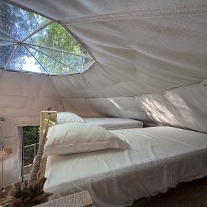 Dôme géodésique lumineux avec lits confortables, offrant une vue sur la nature environnante.