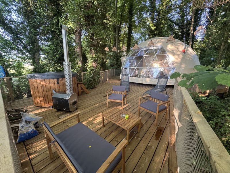 Dôme en pleine nature avec terrasse en bois, coin salon et jacuzzi.