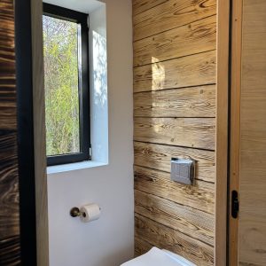 Toilettes modernes en bois, avec fenêtre offrant une vue sur la nature environnante.