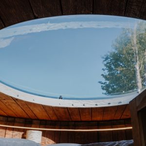 Hébergement insolite : cabane avec un toit en verre, offrant une vue sur le ciel et les arbres.