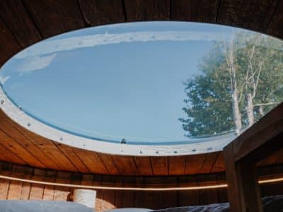 Hébergement insolite : cabane avec un toit en verre, offrant une vue sur le ciel et les arbres.
