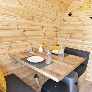 Intérieur d'un chalet en bois, avec une table en bois, des coussins jaunes et des décorations