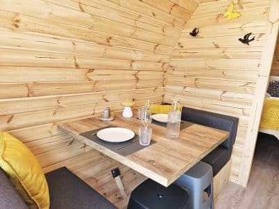 Intérieur d'un chalet en bois, avec une table en bois, des coussins jaunes et des décorations