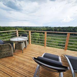 Terrasse en bois d'une cabane perchée, offrant une vue panoramique sur la nature environnante.