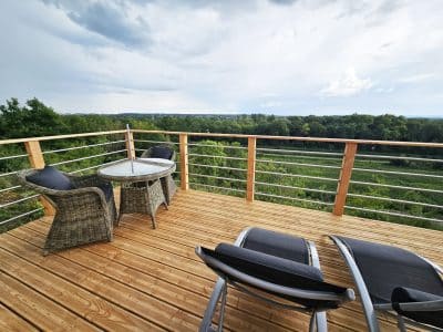 Terrasse en bois d'une cabane perchée, offrant une vue panoramique sur la nature environnante.