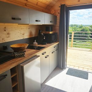 Cottage en bois avec cuisine moderne et vue dégagée sur la nature depuis la terrasse.