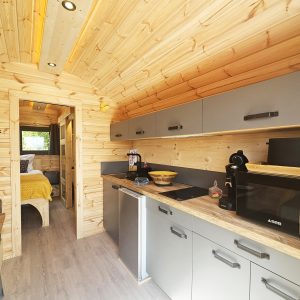 Tiny house en bois avec cuisine moderne et ambiance chaleureuse, idéale pour un séjour cocooning.