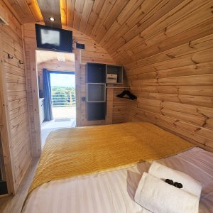 Intérieur d'un hébergement insolite en bois, avec lit douillet et décoration chaleureuse.