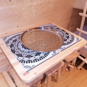Table en bois avec plateau décoratif dans un hébergement insolite en bois.
