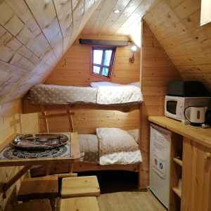 Cabane en bois cosy avec lits superposés, kitchenette et ambiance chaleureuse.