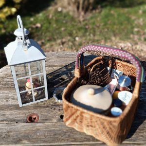 Panier pique-nique en osier sur une table en bois, avec une lanterne et des accessoires colorés.