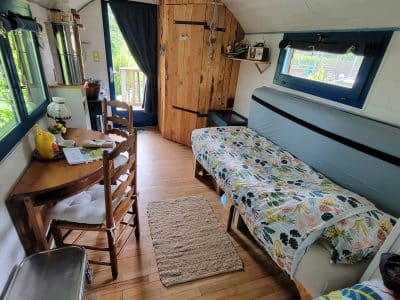 Intérieur d'une tiny house chaleureuse, avec un lit simple, une table en bois et des touches