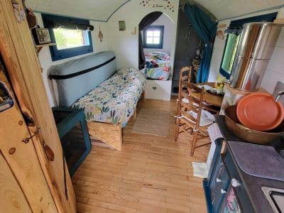Intérieur d'une tiny house colorée, avec lit douillet et cuisine fonctionnelle. Ambiance