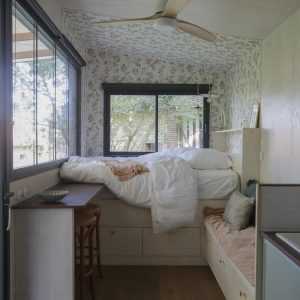 Chambre cosy dans un hébergement insolite, avec lit surélevé et décor floral apaisant.