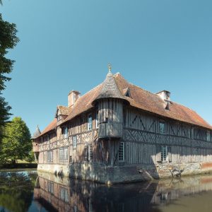 Charmante maison en bois à colombages, entourée d'un étang et de verdure luxuriante.