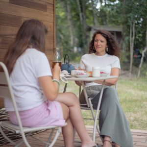 Deux femmes profitent dun petit-déjeuner sur la terrasse dun chalet en bois.