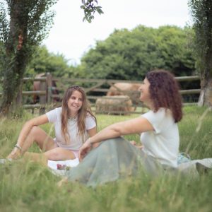 Deux amies profitent d'un pique-nique dans un hébergement insolite, entourées de verdure.