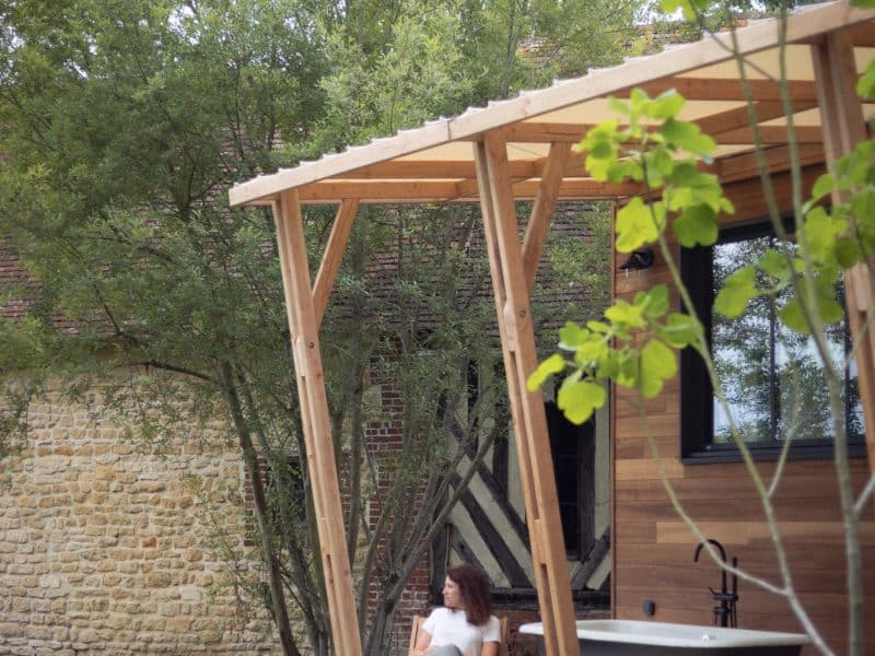 Cabane en bois avec baignoire extérieure, entourée de verdure apaisante.