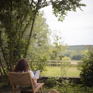 Chalet en pleine nature, avec une vue dégagée sur la verdure et une personne lisant.