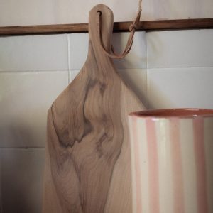Planche en bois et tasse rayée, ambiance chaleureuse d'un hébergement insolite.