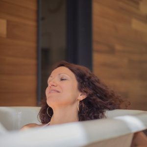 Bain relaxant dans une baignoire moderne, entourée de bois chaleureux et apaisant.