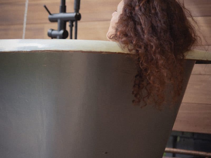 Bain relaxant dans une baignoire vintage, ambiance chaleureuse et boisée.