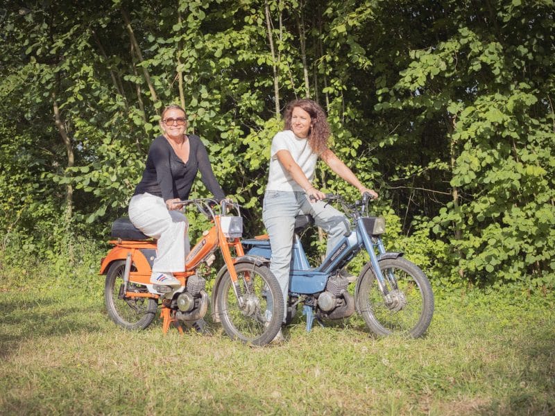 Deux femmes sur des vélos dans un cadre naturel, parfait pour un séjour en camping.