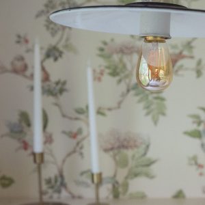 Chambre d'hôtes au décor floral, avec une lampe vintage et des bougies élégantes.