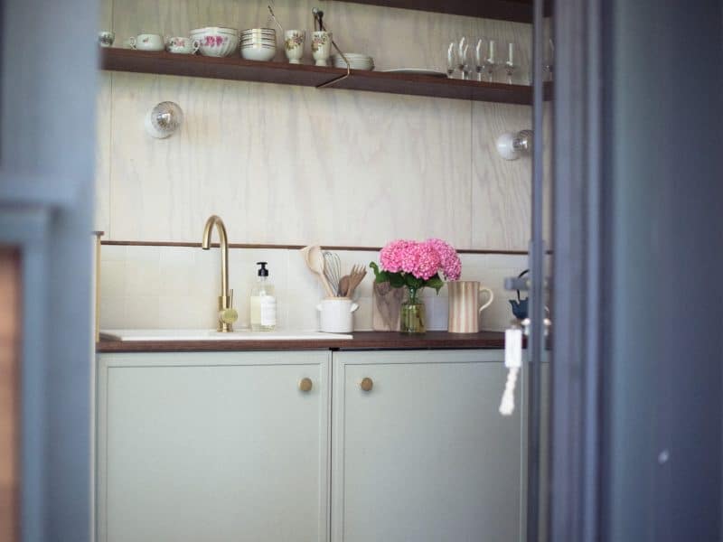 Cuisine moderne dun gîte, avec des fleurs roses et des étagères en bois.