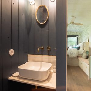 Salle de bain moderne dans un hébergement touristique, avec un lavabo élégant et des murs en bois.