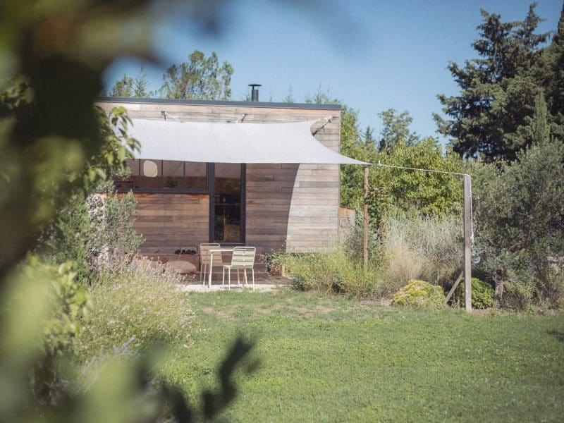 Charmante cabane en bois avec terrasse ombragée et verdure environnante.