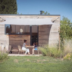 Cabane en bois avec terrasse ombragée, idéale pour un moment de détente en pleine nature.