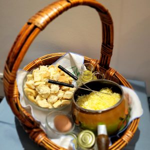 Panier en osier avec fromage, pain et ingrédients pour une fondue savoureuse.