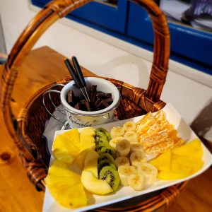 Panier gourmand dans un hébergement insolite, rempli de fruits frais et chocolat.